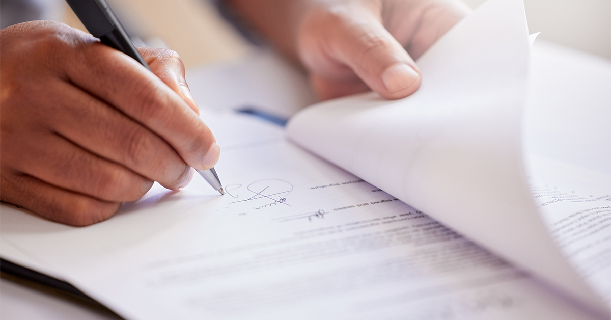 A person's hand signing a legal document.