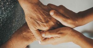 caretaker holding hands of elderly patient